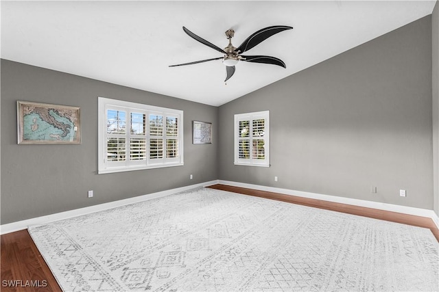 unfurnished room featuring a ceiling fan, lofted ceiling, baseboards, and wood finished floors