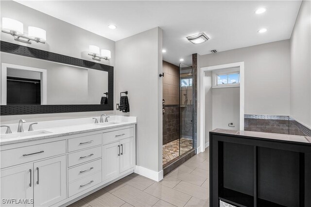 full bathroom featuring double vanity, a stall shower, a sink, and visible vents