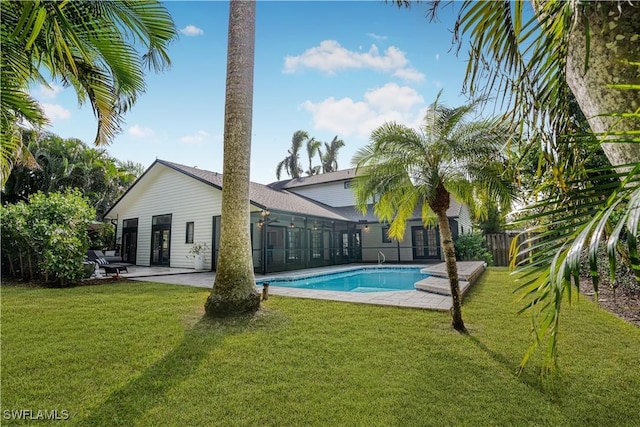 back of property featuring a patio area, an outdoor pool, and a lawn