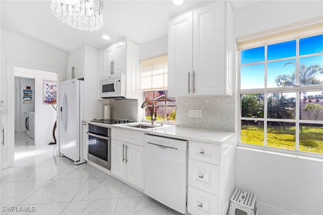 kitchen featuring decorative backsplash, white cabinetry, sink, and white appliances