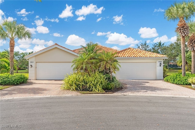 view of front of house featuring a garage, a tile roof, and stucco siding