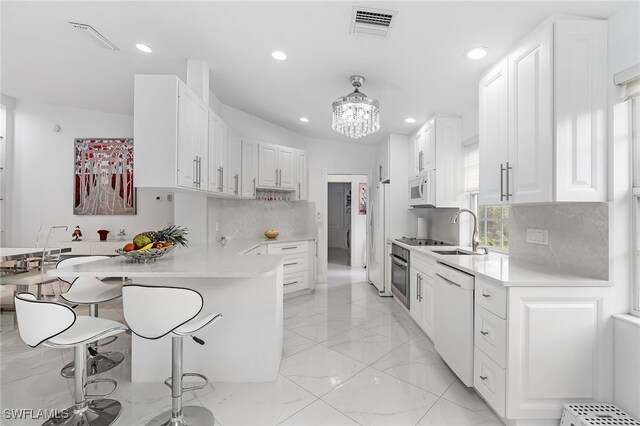 kitchen featuring white cabinets, a kitchen bar, white appliances, and kitchen peninsula