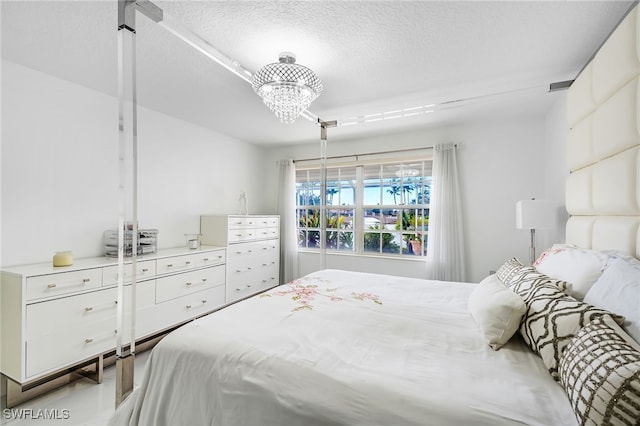 bedroom with a textured ceiling and a chandelier