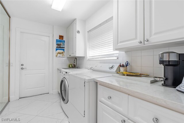 washroom with cabinets, washer and dryer, and sink