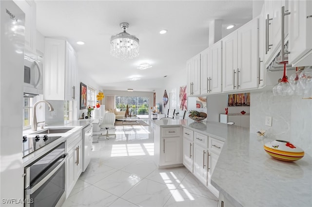 kitchen with stainless steel oven, white cabinets, sink, dishwashing machine, and kitchen peninsula