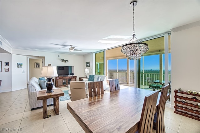 tiled dining space with ceiling fan with notable chandelier, expansive windows, and ornamental molding