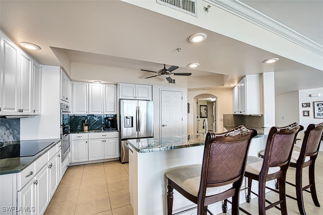 kitchen featuring kitchen peninsula, light tile patterned flooring, white cabinetry, and stainless steel appliances