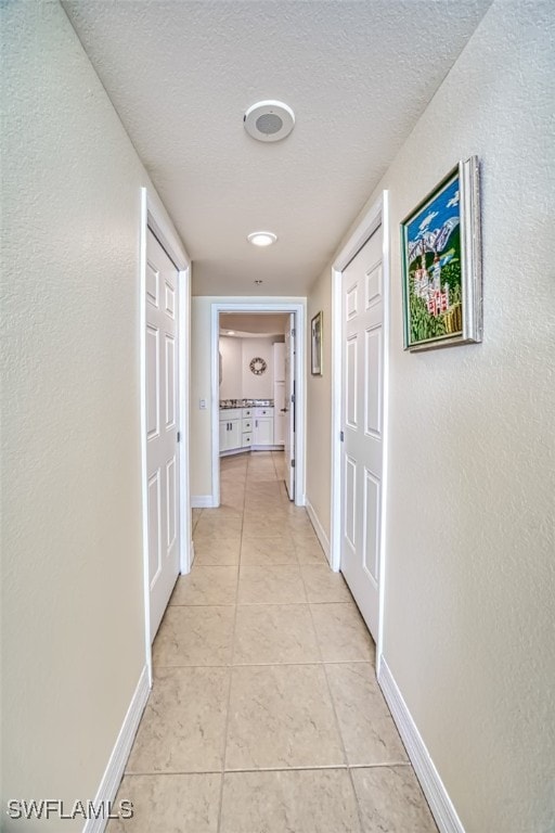 hallway featuring light tile patterned flooring and a textured ceiling