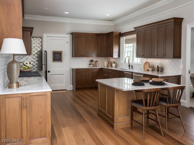 kitchen with dark hardwood / wood-style flooring, decorative backsplash, sink, and a center island