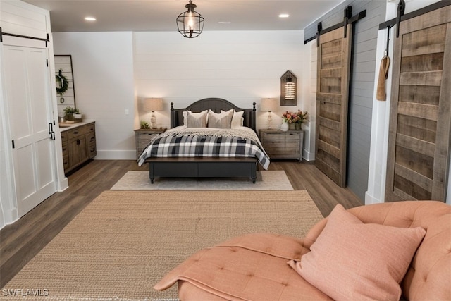 bedroom with a barn door and dark hardwood / wood-style flooring