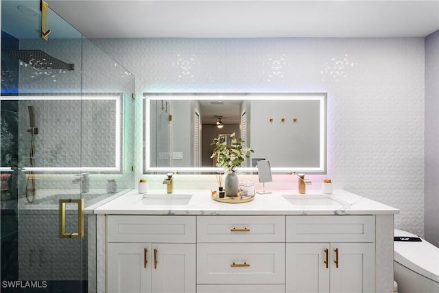 bathroom with vanity, toilet, ceiling fan, and a shower with shower door