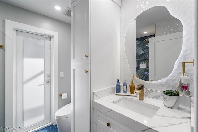 bathroom with toilet, a shower, vanity, and visible vents