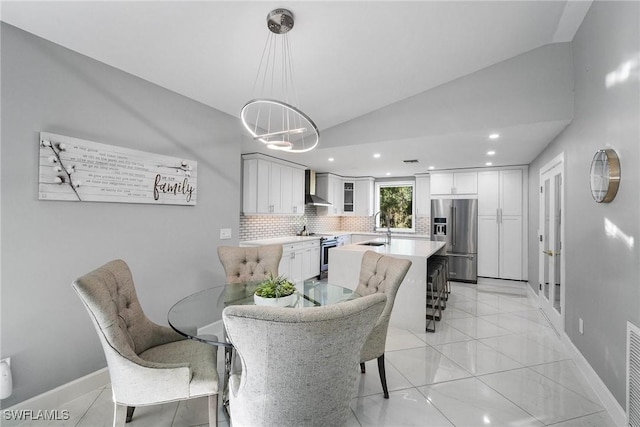 tiled dining space with lofted ceiling and sink