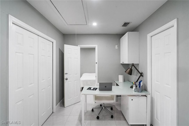 office area with attic access, visible vents, and light tile patterned floors