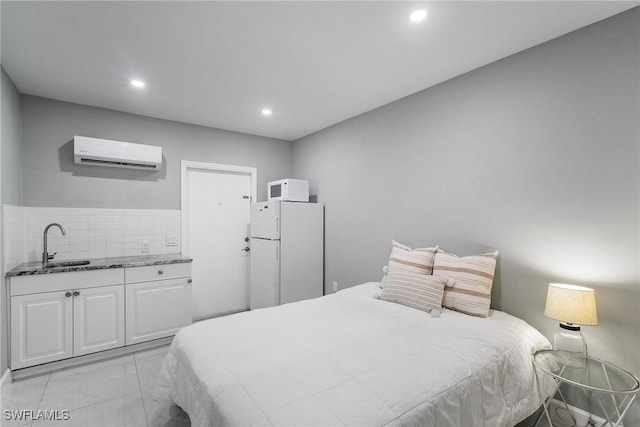 bedroom with white refrigerator, an AC wall unit, and sink