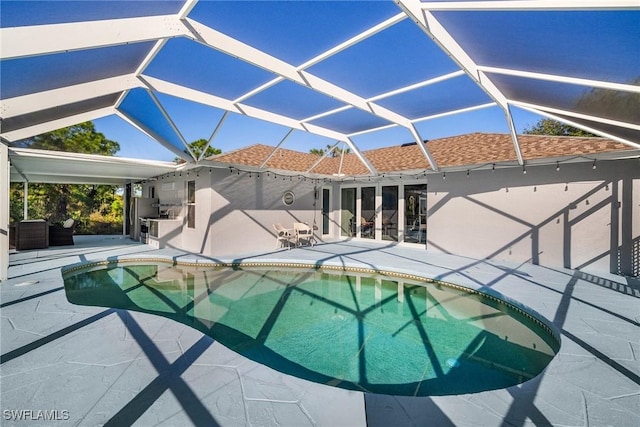 outdoor pool with a patio area, glass enclosure, and area for grilling