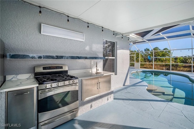 kitchen with a sunroom, a textured wall, and stainless steel gas range oven