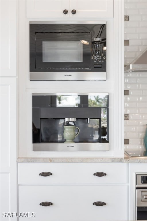 interior details featuring white cabinets, oven, and built in microwave