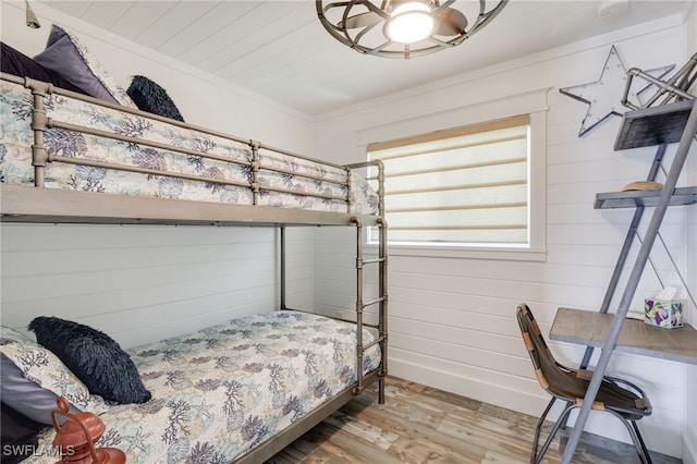 bedroom featuring wood walls, ceiling fan, and light hardwood / wood-style floors