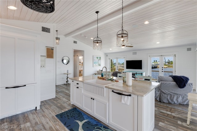 kitchen with sink, light hardwood / wood-style flooring, lofted ceiling with beams, pendant lighting, and a kitchen island with sink