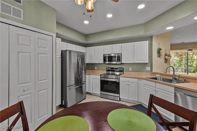 kitchen with white cabinets, sink, ceiling fan, appliances with stainless steel finishes, and light tile patterned flooring