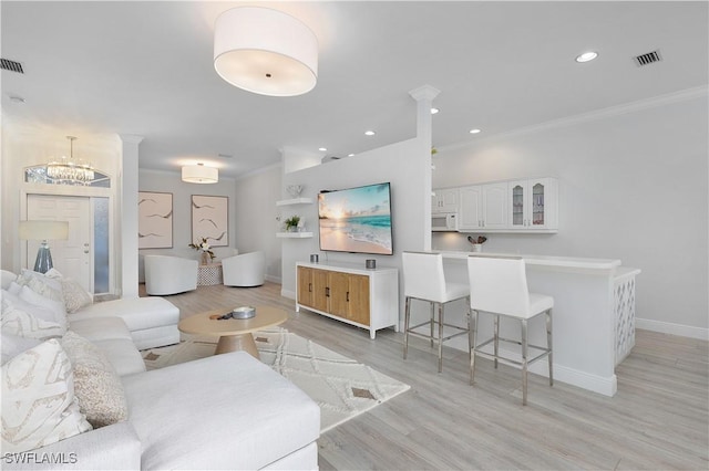 living room featuring light wood-type flooring, crown molding, and a chandelier