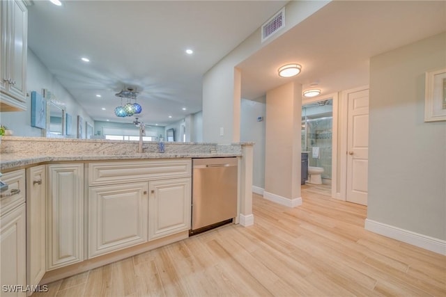 kitchen with light stone counters, dishwasher, sink, and light wood-type flooring