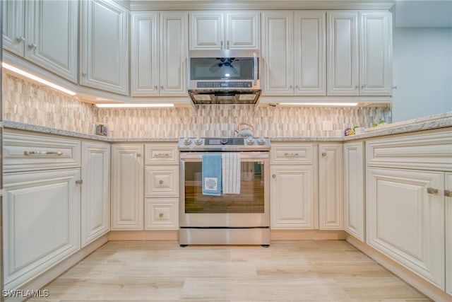 kitchen featuring light stone countertops, appliances with stainless steel finishes, backsplash, and light hardwood / wood-style floors