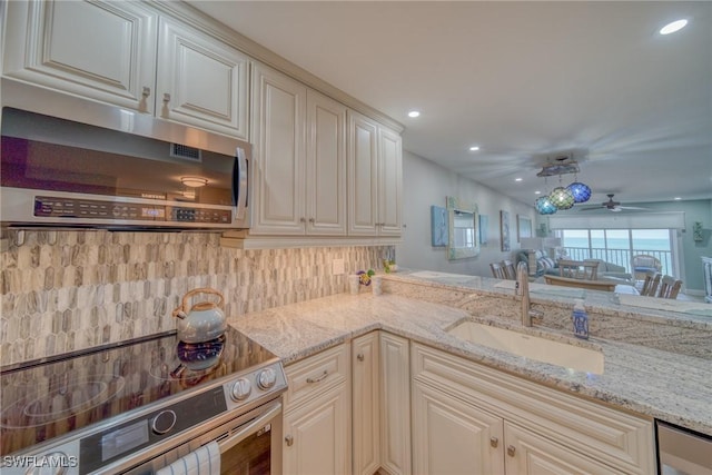 kitchen with light stone counters, stove, sink, and cream cabinets