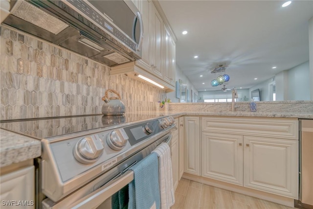 kitchen featuring light hardwood / wood-style flooring, electric range, tasteful backsplash, light stone counters, and kitchen peninsula