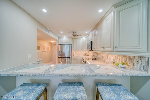 kitchen with kitchen peninsula, appliances with stainless steel finishes, and a breakfast bar area