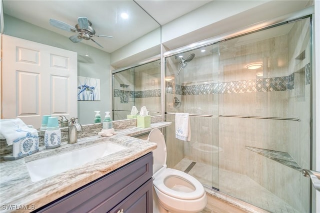 bathroom featuring ceiling fan, wood-type flooring, an enclosed shower, toilet, and vanity