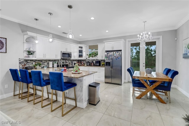 kitchen with hanging light fixtures, stainless steel appliances, backsplash, kitchen peninsula, and white cabinets