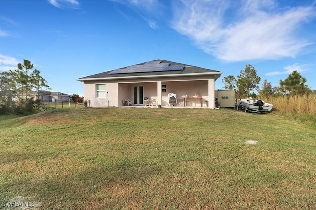 back of property with a lawn, a patio area, and solar panels