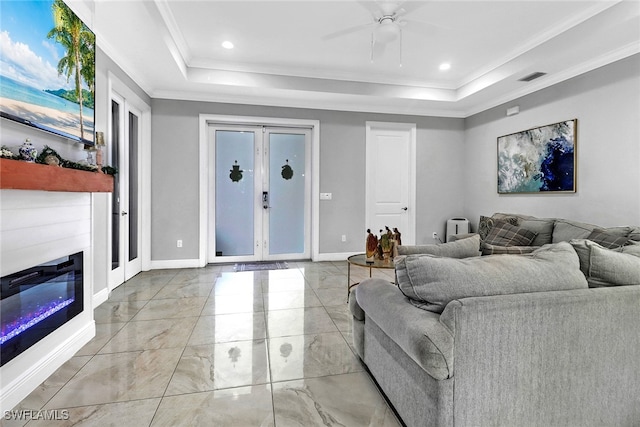 living room featuring a raised ceiling, crown molding, and ceiling fan