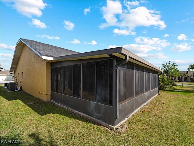 view of property exterior with a lawn, a sunroom, and central AC