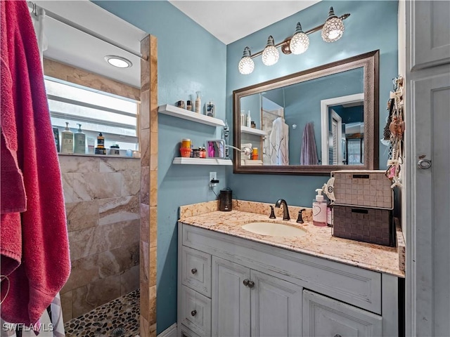 bathroom with a tile shower and vanity