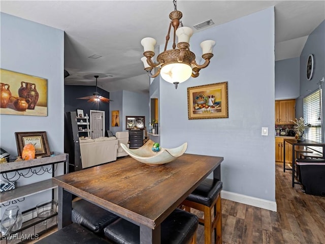 dining area featuring ceiling fan with notable chandelier, dark wood-type flooring, and vaulted ceiling