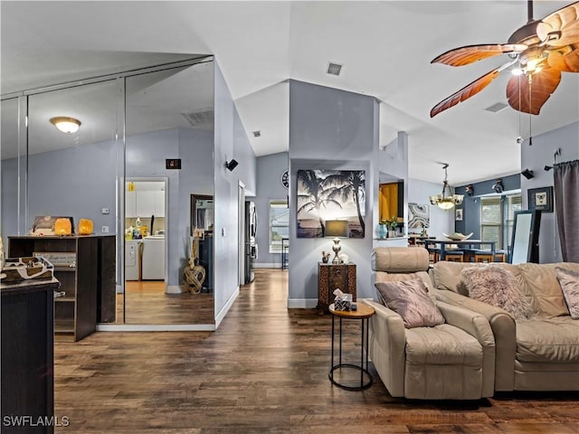 living room with ceiling fan with notable chandelier, dark hardwood / wood-style floors, vaulted ceiling, and washer / dryer