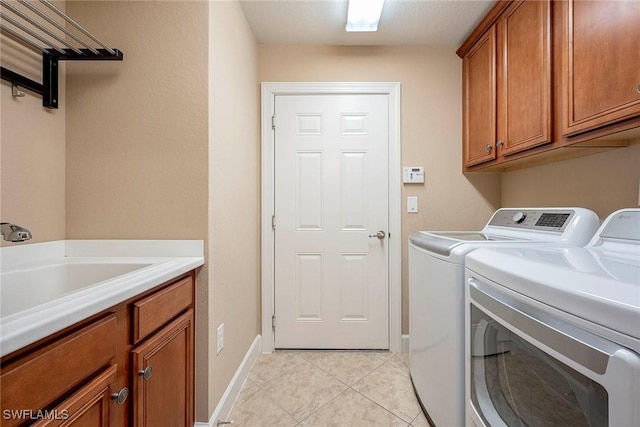 clothes washing area featuring cabinets, light tile patterned floors, sink, and washing machine and clothes dryer