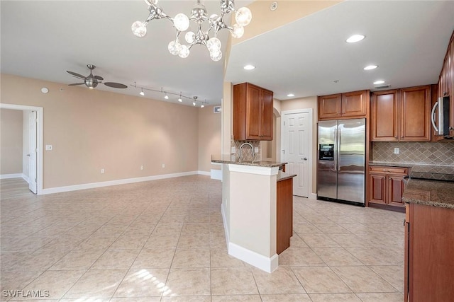 kitchen featuring kitchen peninsula, tasteful backsplash, stainless steel appliances, hanging light fixtures, and light tile patterned flooring