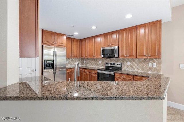 kitchen with kitchen peninsula, decorative backsplash, stainless steel appliances, and stone counters