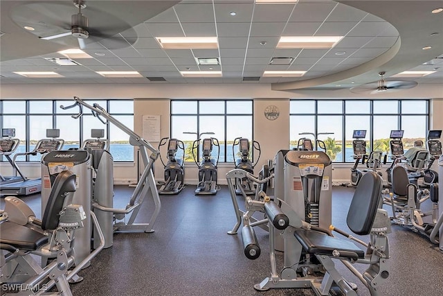 workout area featuring a water view, a drop ceiling, and ceiling fan