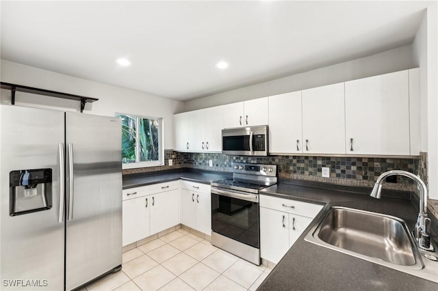 kitchen with appliances with stainless steel finishes, backsplash, white cabinetry, and sink