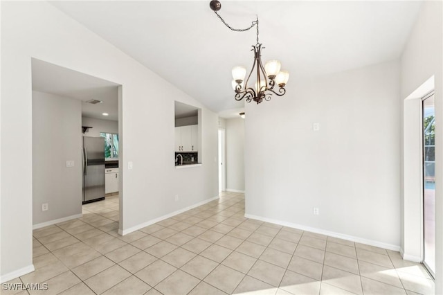 spare room featuring light tile patterned floors and a chandelier