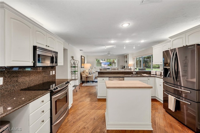 kitchen featuring appliances with stainless steel finishes, rail lighting, ceiling fan, sink, and white cabinetry