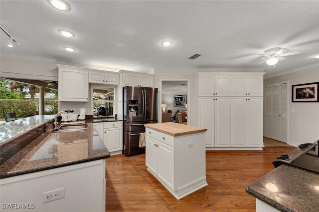 kitchen with sink, light hardwood / wood-style flooring, white cabinets, stainless steel fridge with ice dispenser, and a center island