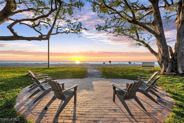 patio terrace at dusk featuring a water view and a yard