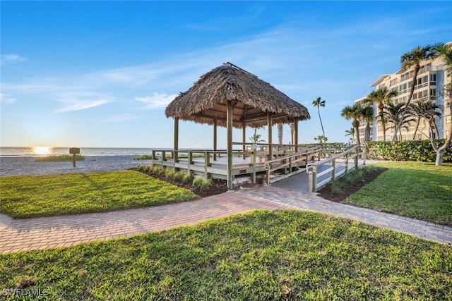 view of dock with a gazebo, a water view, and a lawn