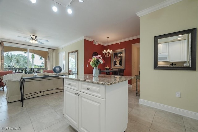 kitchen featuring ornamental molding, ceiling fan with notable chandelier, pendant lighting, a center island, and white cabinetry